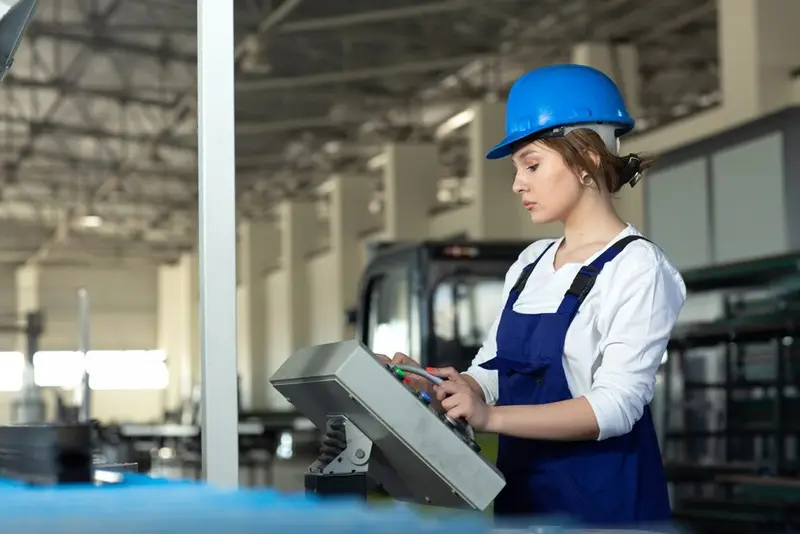 A TFM technician in a hard hat operating production machinery on the factory floor